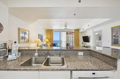 a kitchen with a sink and a living room at Shores of Panama 1717 - 1 Bedroom Bunk room Sleeps 6, Gulf-Front with Oversized Balcony! condo in Panama City Beach
