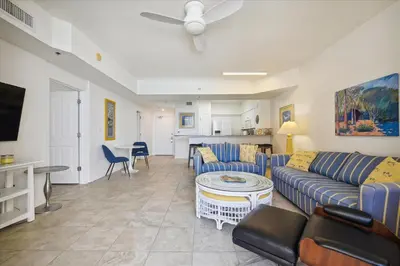 a living room with blue couches and a kitchen at Shores of Panama 1717 - 1 Bedroom Bunk room Sleeps 6, Gulf-Front with Oversized Balcony! condo in Panama City Beach