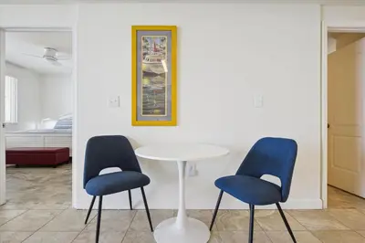 a table and two blue chairs in a room at Shores of Panama 1717 - 1 Bedroom Bunk room Sleeps 6, Gulf-Front with Oversized Balcony! condo in Panama City Beach