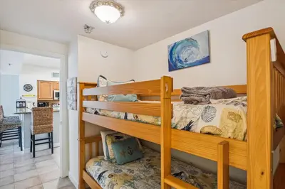 a bedroom with two bunk beds and a kitchen at Shores of Panama 1418 - 2 BedroomBunkroom Sleeps8! Updated with a View! Free Fun! condo in Panama City Beach