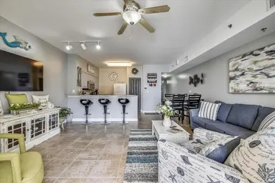 a living room with a blue couch and a kitchen at Shores of Panama 1704 - 2 Bedroom Bunk Room Sleeps 8, Updated! Res, Parking condo in Panama City Beach