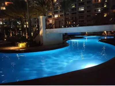 a large pool with blue lights in a city at night at Shores of Panama 521 - 2 Bedroom Bunks Sleeps 6, Reserved Parking! condo in Panama City Beach