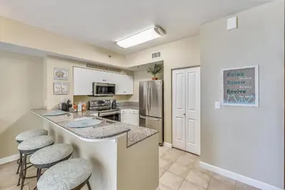 a kitchen with a counter with stools and a refrigerator at Shores of Panama 808- 1 BedroomBunk Room, Free Fun! Updated! Sleeps 6, condo in Panama City Beach