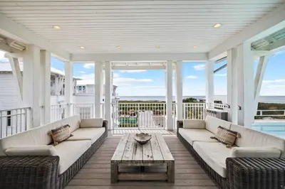 a screened in porch with couches and a coffee table at Beach Gulf Views with a 3rd Floor Pool - Mala House - Inlet Beach, FL home in Inlet Beach