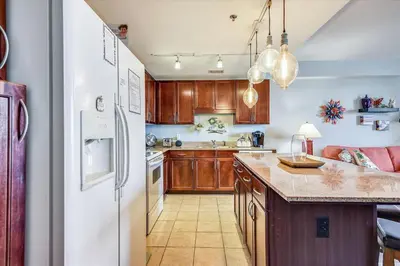 a kitchen with wooden cabinets and a white refrigerator at Laketown Wharf 835 - Very Cool 1 BedroomBunks, Sleeps 6, Free Fun! condo in Panama City Beach