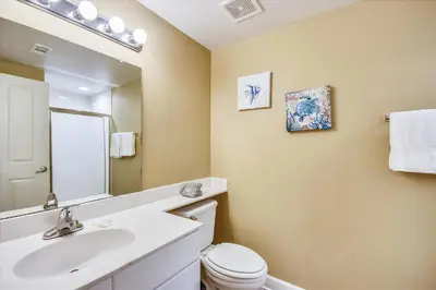 a bathroom with a sink and a toilet and a mirror at Shores of Panama 1804 - 2 Bedroom Bunkroom Sleeps 8, Updated! Free Fun, condo in Panama City Beach