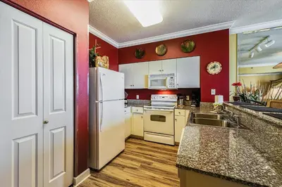 a kitchen with red walls and a white refrigerator at Shores of Panama 707 - 2 BedroomBunks Sleeps 8, Reserved Parking Free Fun! condo in Panama City Beach