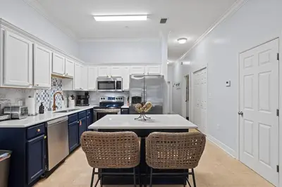 a kitchen with white cabinets and a table and chairs at Happy Days - Seagrove Highlands in Santa Rosa Beach