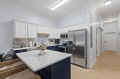 a kitchen with a stainless steel refrigerator and blue cabinets at Happy Days - Seagrove Highlands in Santa Rosa Beach