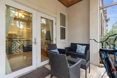 a porch with chairs and a table and a door at Happy Days - Seagrove Highlands in Santa Rosa Beach