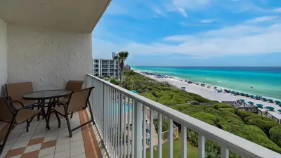 a balcony with a table and chairs and the beach at Beachcrest 405 in Santa Rosa Beach