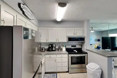 a kitchen with white cabinets and a black refrigerator at Endless Summer #A27 in Panama City Beach
