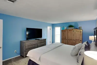 a blue bedroom with a bed and a television at Endless Summer #A27 in Panama City Beach