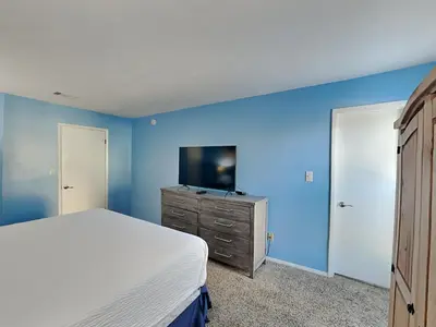 a bedroom with blue walls and a bed and a dresser at Endless Summer #A27 in Panama City Beach