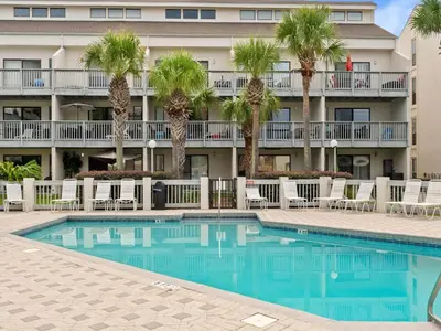 a swimming pool in front of a hotel with palm trees at Endless Summer #A27 in Panama City Beach