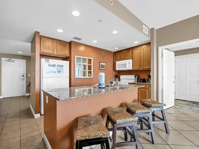 a kitchen with a counter and stools in a room at Sterling Reef 1203 in Panama City Beach