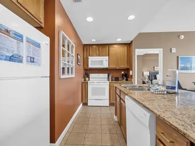 a kitchen with wooden cabinets and white appliances at Sterling Reef 1203 in Panama City Beach