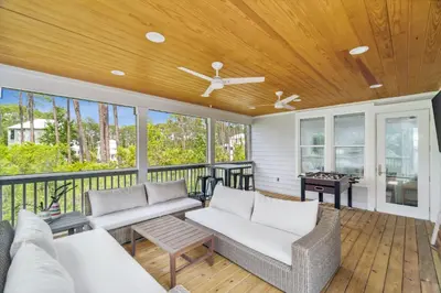 a porch with white furniture and a wooden ceiling at 30A Beach House - Wonderland at Treetop by Panhandle Getaways in Rosemary Beach