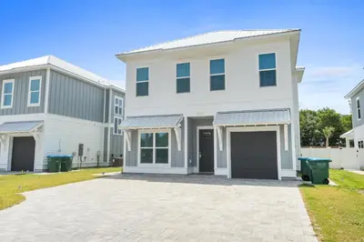 a white house with a garage in a yard at Pet Friendly Beach House - Totally Beachin by Panhandle Getaways in Panama City Beach