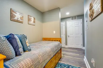 a small bedroom with a bed and a white door at PCB Vacation Rental with Balcony and Beach Access! in Panama City Beach