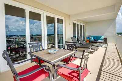 a patio with a wooden table and chairs on a balcony at PCB Vacation Rental with Balcony and Beach Access! in Panama City Beach