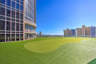 a building with a green field in front of a building at PCB Vacation Rental with Balcony and Beach Access! in Panama City Beach