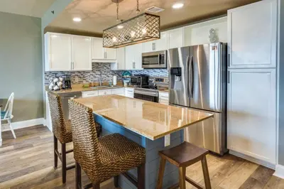 a kitchen with white cabinets and a refrigerator at PCB Vacation Rental with Balcony and Beach Access! in Panama City Beach