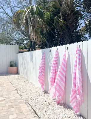 a white fence with pink and white towels on it at Steps to the beach & close to 30A! Private pool with sundeck & putt putt golf! in Panama City Beach