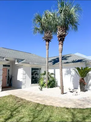 two palm trees in front of a house at Steps to the beach & close to 30A! Private pool with sundeck & putt putt golf! in Panama City Beach