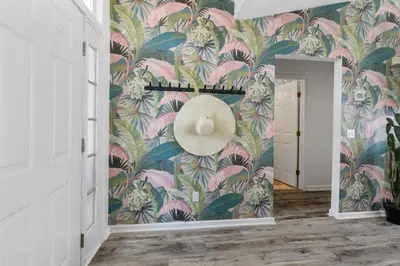 a hallway with a pink and green floral wallpaper at Steps to the beach & close to 30A! Private pool with sundeck & putt putt golf! in Panama City Beach