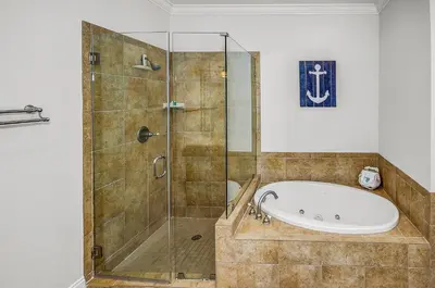 a bathroom with a tub and a glass shower at 136 La Valencia Cir - At Peace in Panama City Beach