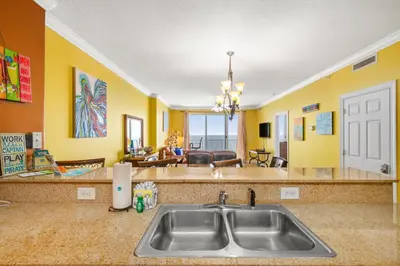 a kitchen with a sink and a living room at Ocean Reef 1106 - Lazy Daze in Panama City Beach