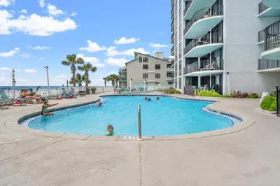 a swimming pool at a resort with people in it at Stunning 2/2 Designer Condo w Coastal Appeal Right on the Gulf! in Panama City Beach