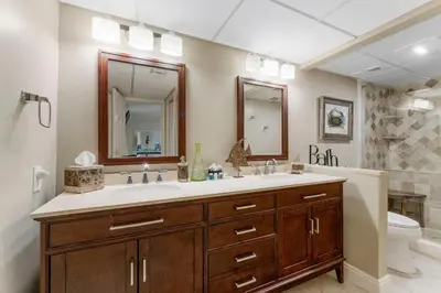 a bathroom with a sink and a toilet and a mirror at Stunning 2/2 Designer Condo w Coastal Appeal Right on the Gulf! in Panama City Beach