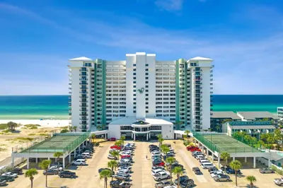 a large building with cars parked in a parking lot at Stunning 2/2 Designer Condo w Coastal Appeal Right on the Gulf! in Panama City Beach