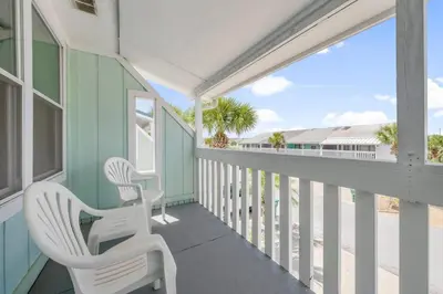 a balcony with white chairs and a view of the beach at NEW! Steps To White Sand Beaches! Pool & Grill! 2BR 2BA in Panama City Beach