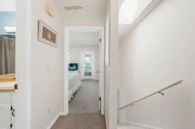 a white hallway with a bedroom and a bed at NEW! Steps To White Sand Beaches! Pool & Grill! 2BR 2BA in Panama City Beach