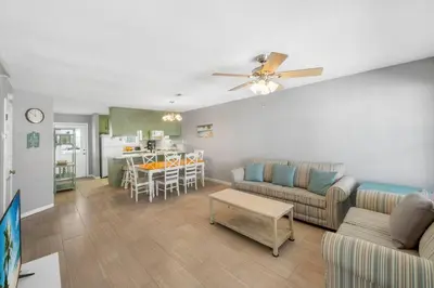 a living room with a couch and a table at NEW! Steps To White Sand Beaches! Pool & Grill! 2BR 2BA in Panama City Beach