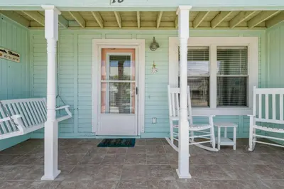 a front porch with two chairs and a door at NEW! Steps To White Sand Beaches! Pool & Grill! 2BR 2BA in Panama City Beach
