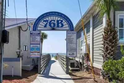 a sign in front of a building with a clock at NEW! Steps To White Sand Beaches! Pool & Grill! 2BR 2BA in Panama City Beach