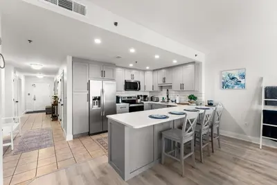 a kitchen with white cabinets and a kitchen island with bar stools at Luxury Gulf-View 3BD Condo! Free Beach Chairs! by Dolce Vita Getaways PCB in Panama City Beach