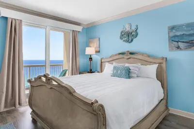 a bedroom with a bed with blue walls and a window at Seychelles 1601 in Panama City Beach