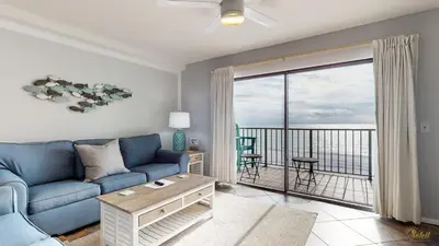 a living room with a blue couch and a balcony at Beachfront - Beach Chairs Included! - FLPCB53 in Panama City Beach