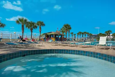 a swimming pool next to a beach with palm trees at Beachfront - Beach Chairs Included! - FLPCB53 in Panama City Beach