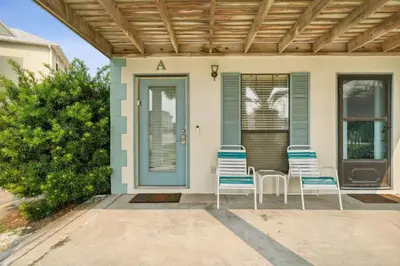two chairs and a table on the front porch of a house at Sandcastle In The Sun in Panama City Beach
