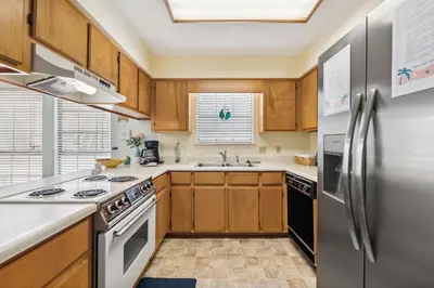a kitchen with wooden cabinets and a stainless steel refrigerator at Sandcastle In The Sun in Panama City Beach