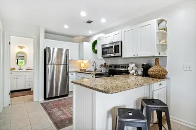 a kitchen with white cabinets and a stainless steel refrigerator at 30A Beachwood Villas by Panhandle Getaways in Santa Rosa Beach