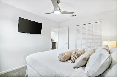 a white bedroom with a bed and a flat screen tv at 30A Beachwood Villas by Panhandle Getaways in Santa Rosa Beach