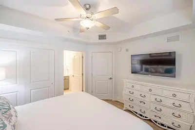 a white bedroom with a bed and a ceiling fan at Calypso 3-903 - Emerald Getaway in Panama City Beach