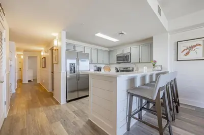 a kitchen with white cabinets and a counter with chairs at Calypso 3-903 - Emerald Getaway in Panama City Beach